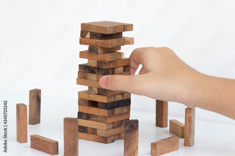 hand pulling out or placing wood block on the tower in modern office, plan and strategy in business with white background. hand pulling out or placing wood block on the tower in modern office, plan and strategy in business with white background.