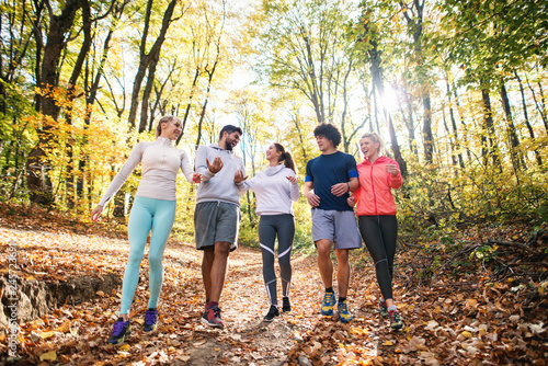 Group of runners walking in the woods and talking. Autumn season.