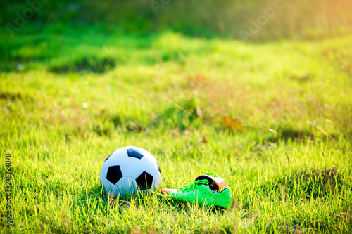 football and soccer shoes on the green grass for soccer player training