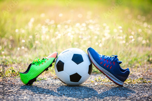 football and soccer shoes with blurry of green grass for soccer player training