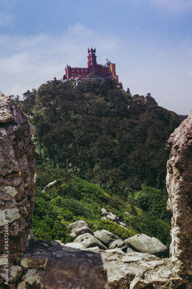 Beautiful palace of Pena, wich is seen from the Moorish castle. View of the castle on the top of a hill in the Sintra Mountains. Romanticism architecture. Famous Portuguese Riviera landmark. Portugal.