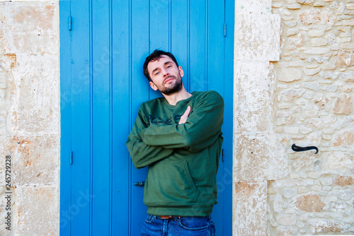 The Greek man poses against the background of a blue door © julijacernjaka