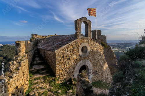 View of Palafolls castle medieval ruined stronghold between Girona and Barcelona on the Costa Brava with the Catalan flag proudly flying over the Romanesque church photo