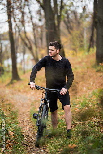 Attractive young caucasian man bicycling in the park. Outdoors, autumn fall park. Copy space.