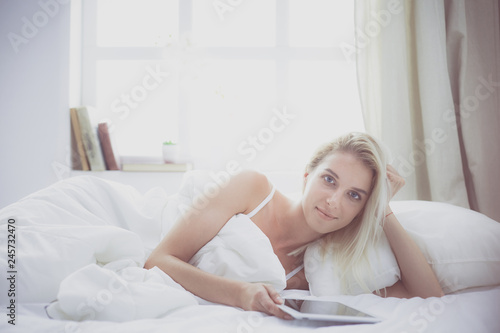 Girl holding digital tablet with blank screen and smiling at camera in bedroom