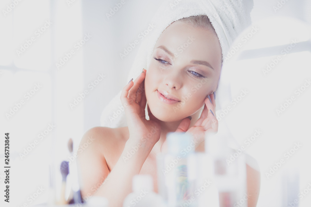 Young woman in bathrobe looking in bathroom mirror Young woman in bathrobe looking in bathroom mirror