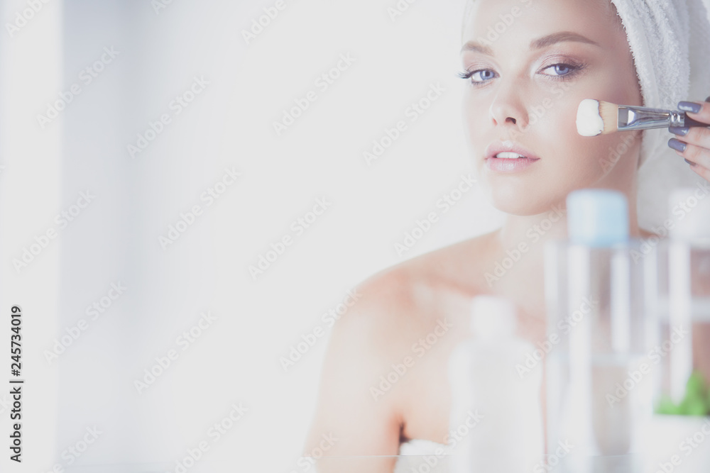A picture of a young woman applying face powder in the bathroom A picture of a young woman applying face powder in the bathroom