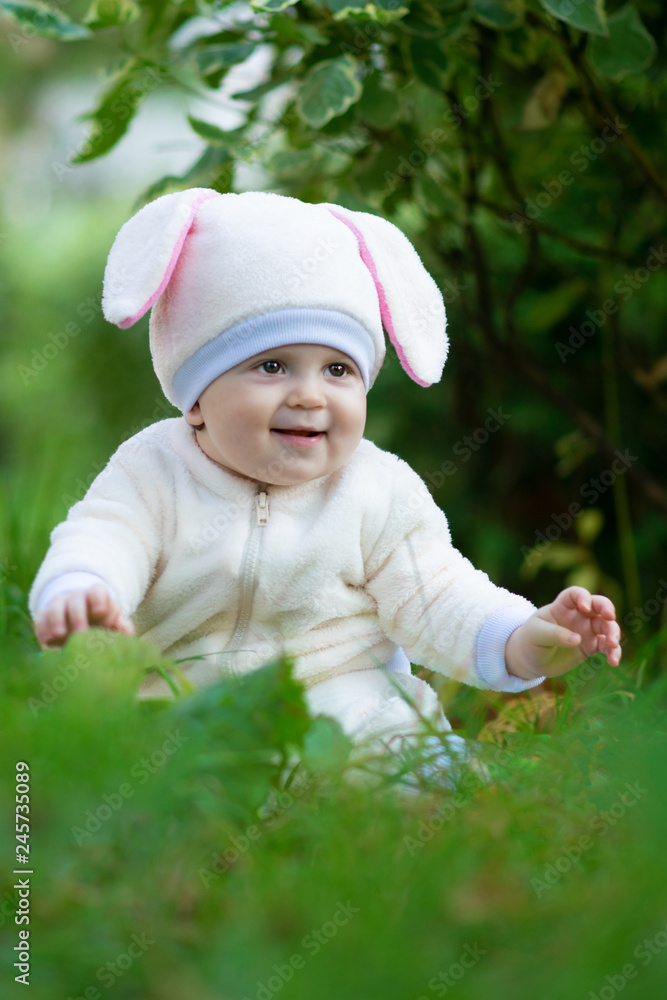 Child in bunny suit seating on grass in park. Child in bunny suit seating on grass in park.