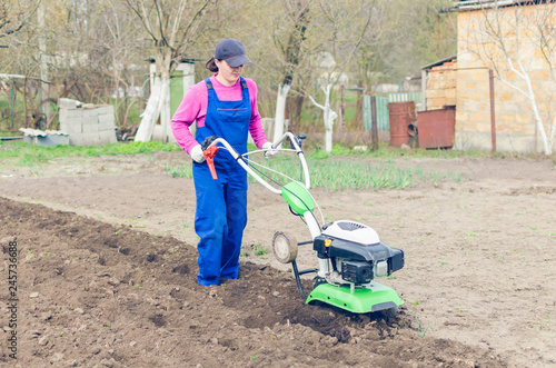 Young girl working in a spring garden with a cultivator