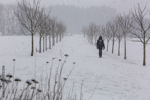 Man vandrar genom en allé vid snöfall