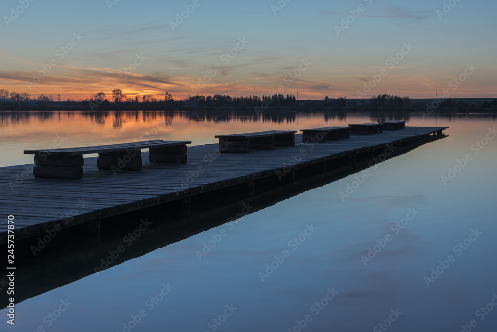 A long bridge with benches, beauty sunset over a calm lake
