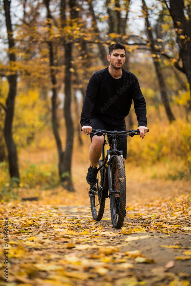 Obraz premium Young fit man during a bike ride on a sunny day in autumn park