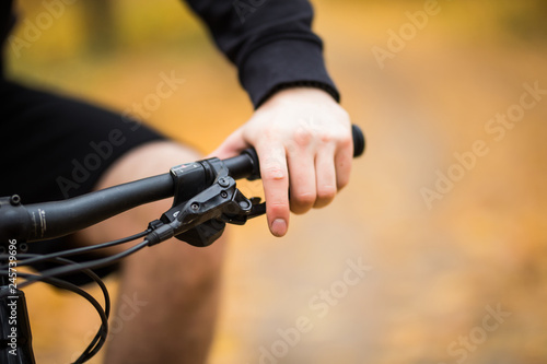 Biker's hand on the handlebars while ride in autumn park close up