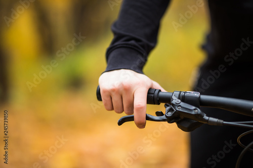 Biker's hand on the handlebars while ride in autumn park close up