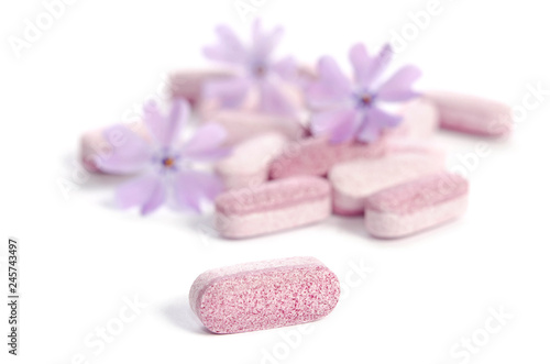 heap of medicine tablets with flowers isolated on white background