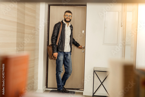 Handsome short-haired bearded man with a bag leaving the room photo