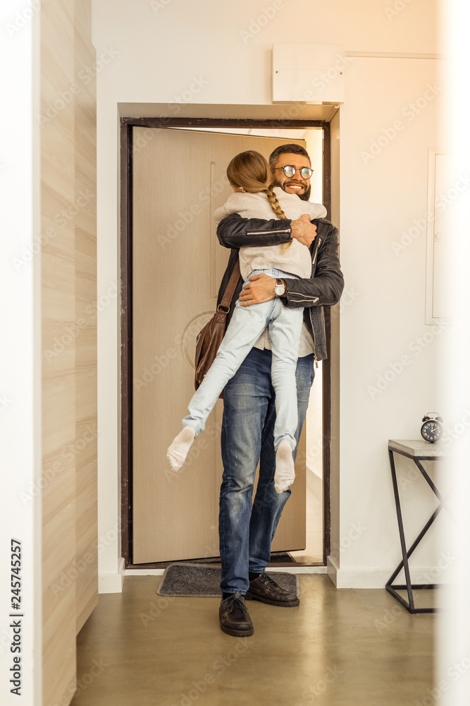 Attractive tall short-haired bearded man from generation Y holding his daughter Attractive tall short-haired bearded man from generation Y holding his daughter