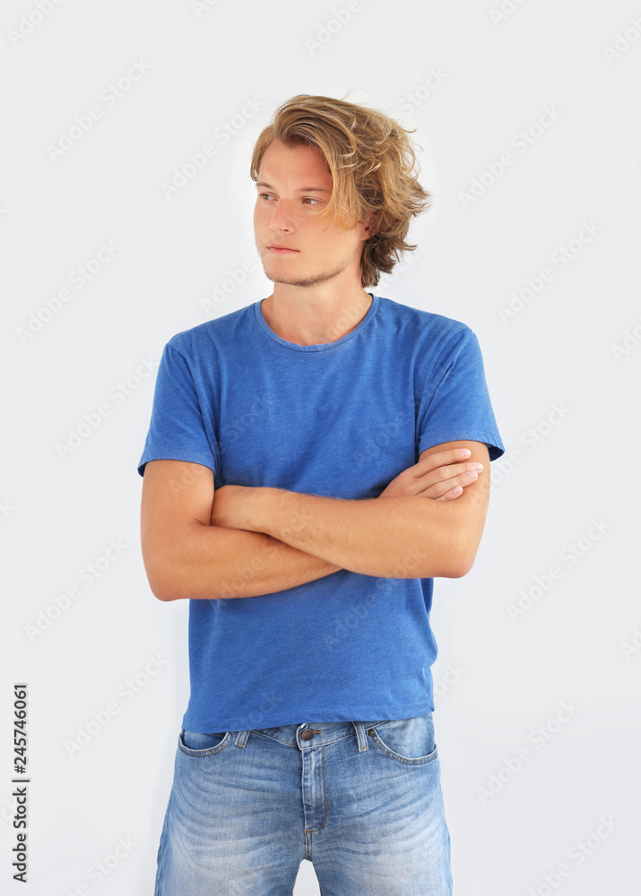 Portrait of attractive teenage boy standing in front of a gray wall. Portrait of attractive teenage boy standing in front of a gray wall.