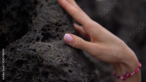 Woman hands with light-coloured manicure and nice missanga touching black stone photo