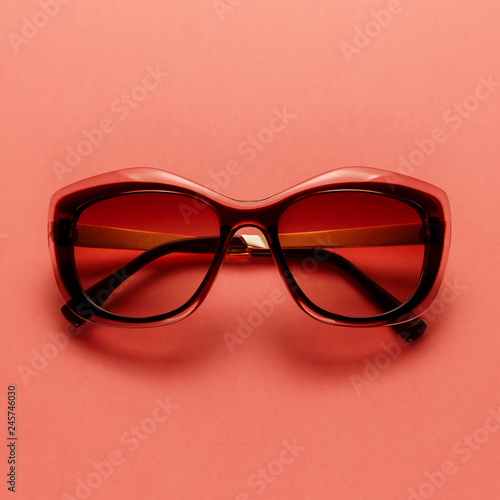 Fashion sunglasses on coral background. Top view. Flat lay. Copy space. New minimal creative concept. Summer is coming concept. Living Coral color of the Year 2019