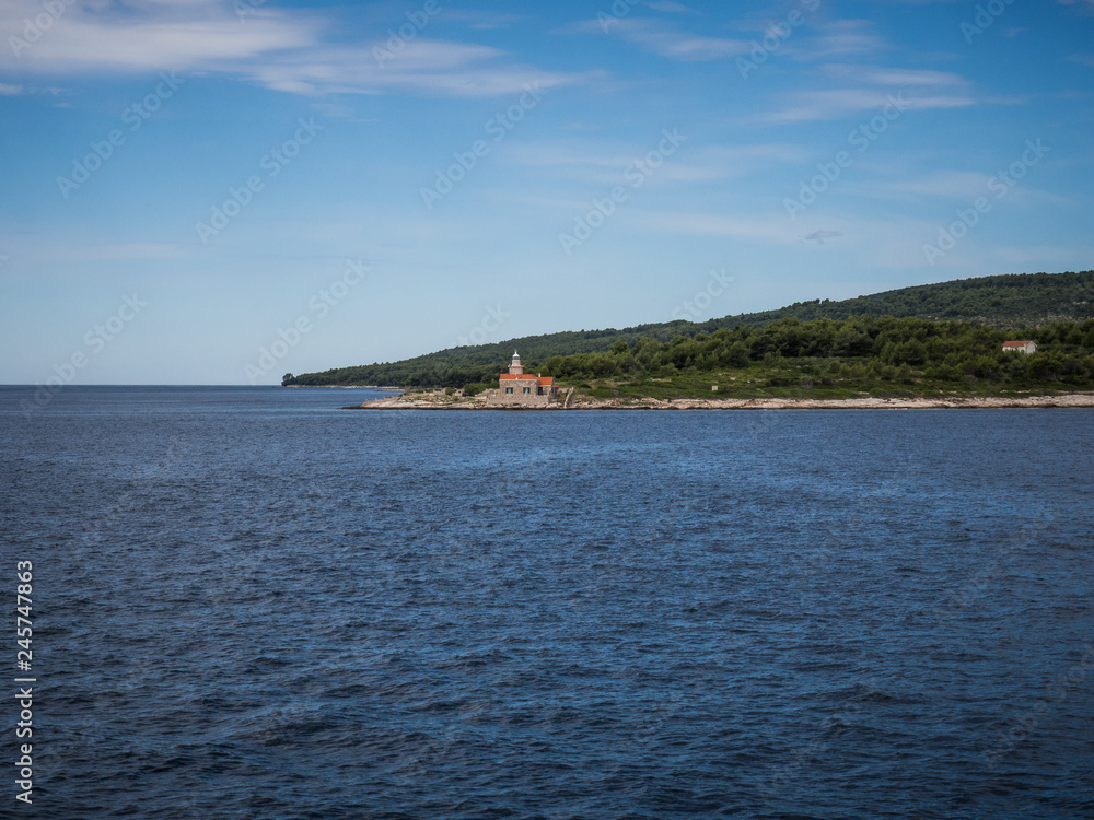 Ferry passing close to Sucuraj lighthouse on Hvar island, Croatia