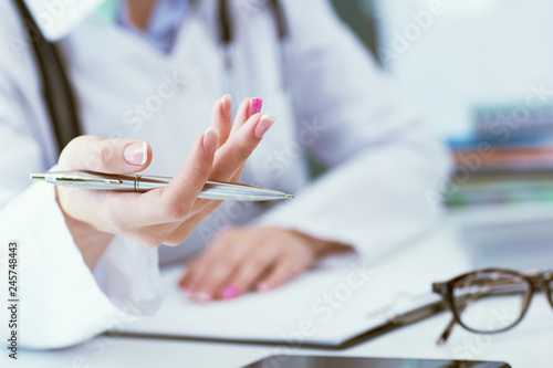 Female doctor explaining patient symptoms or asking a question as they discuss together in a consultation. Just hands over the table.