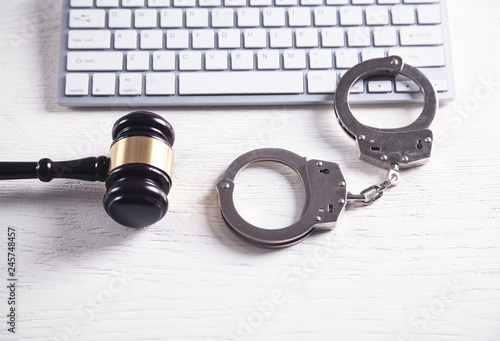 Handcuffs and Judge Gavel with computer keyboard. Concept of Cyber crime and Online fraud