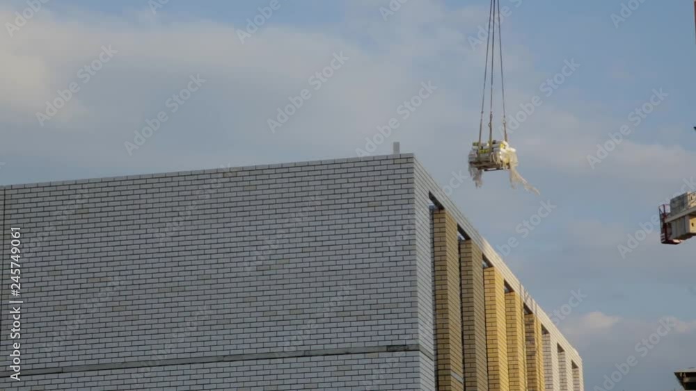 Crane lifts building materials to the construction of multi-storey buildings Crane lifts building materials to the construction of multi-storey buildings