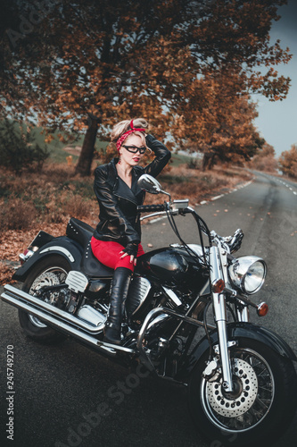 Beautiful biker woman posing outdoor with motorcycle. Pin-up style. 