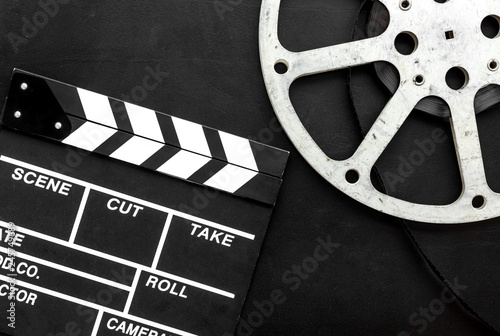 Filmings concept. Clapperboard and film stock on black background top view copy space