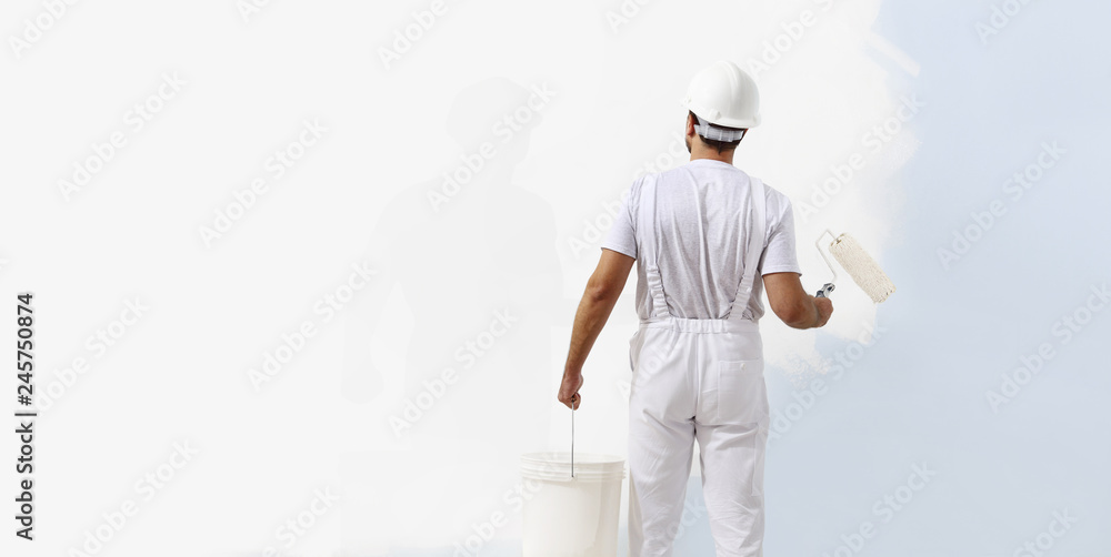 Rear view of painter man painting the wall, with paint roller and bucket, isolated on big empty white copy space template Rear view of painter man painting the wall, with paint roller and bucket, isolated on big empty white copy space template