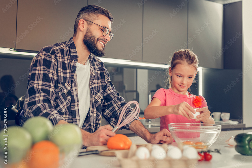 Girl with long hair making omelet with her father