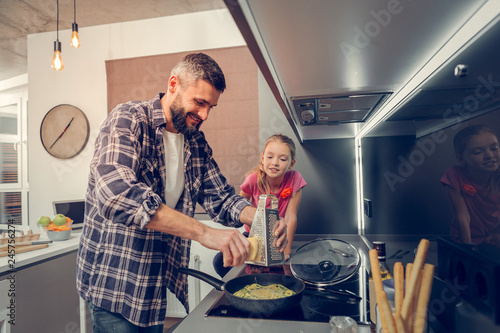 Bearded tall man in a checkered shirt adding cheese to the omelet