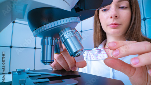 Φωτογραφία Young woman technician is examining a histological sample, a biopsy in the labor