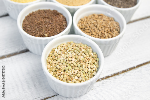 Collection of different groats on grey background. Top view of buckwheat, chia, flax, amaranth, lentils, couscous, wheat © Анна Бортникова