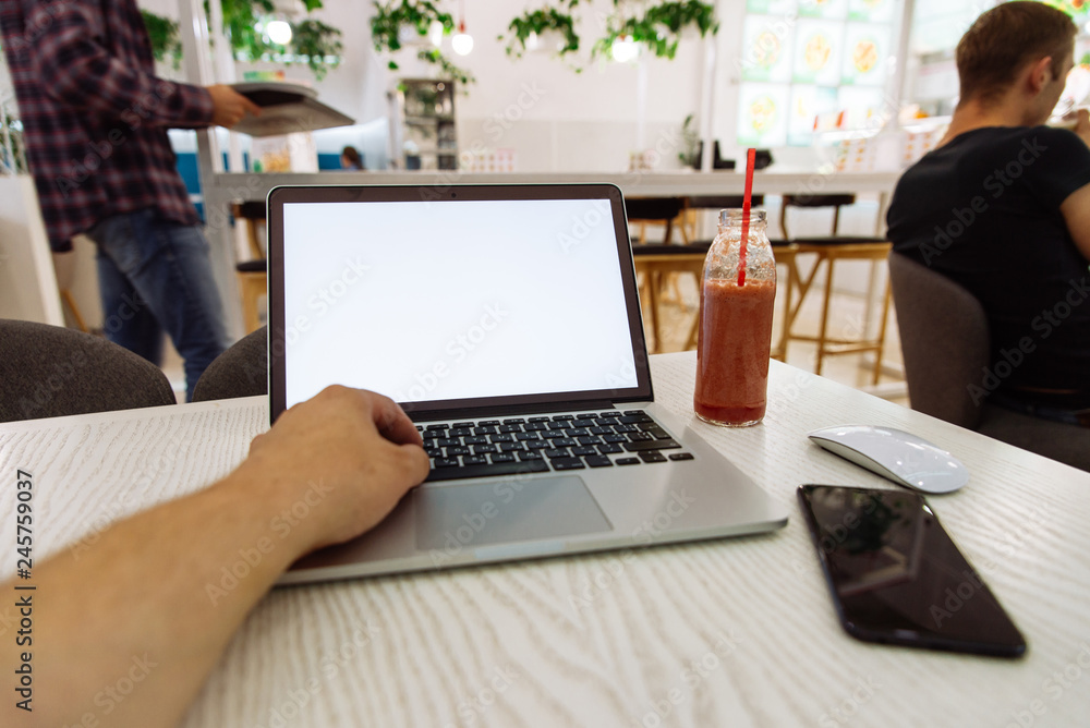 laptop in cafe table with white screen and fruit smoothie near it laptop in cafe table with white screen and fruit smoothie near it