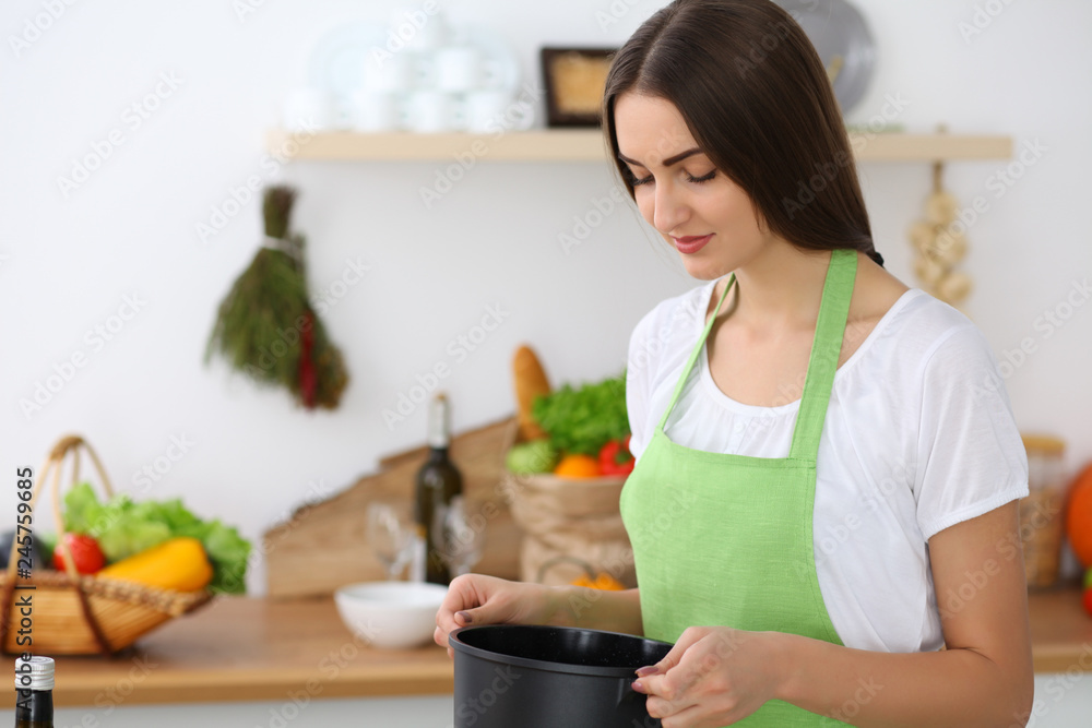 Beautiful Hispanic woman cooking soup in kitchen. Healthy meal and householding concepts