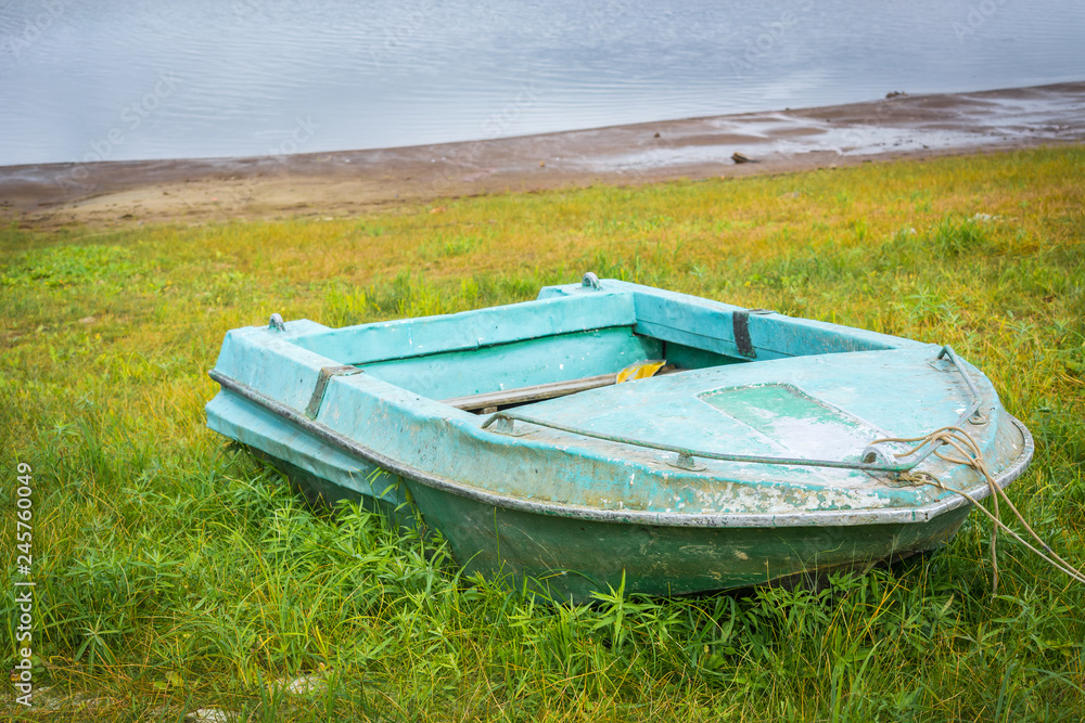 Green empty boat for fishing stands on grass with leash. Green empty boat for fishing stands on grass with leash.