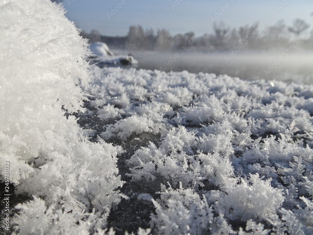 Crystals of snowflakes on the background of a winter landscape with a river.
