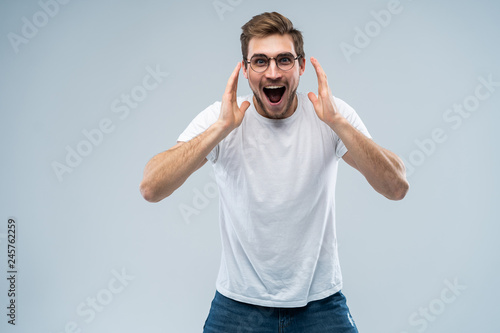 Portrait of young amazed man isolated on gray background.