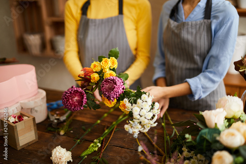 Crop portrait of two unrecognizable florists holding beautiful bouquets at counter in flower shop  copy space