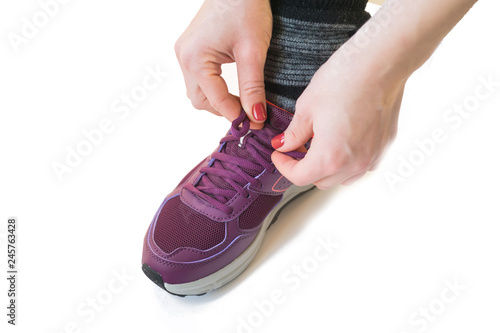 woman tying shoelaces in running shoes isolated on white