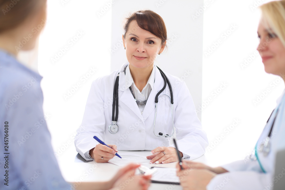 Happy smiling female patient with two cheerful doctors in the background. Happy smiling female patient with two cheerful doctors in the background.