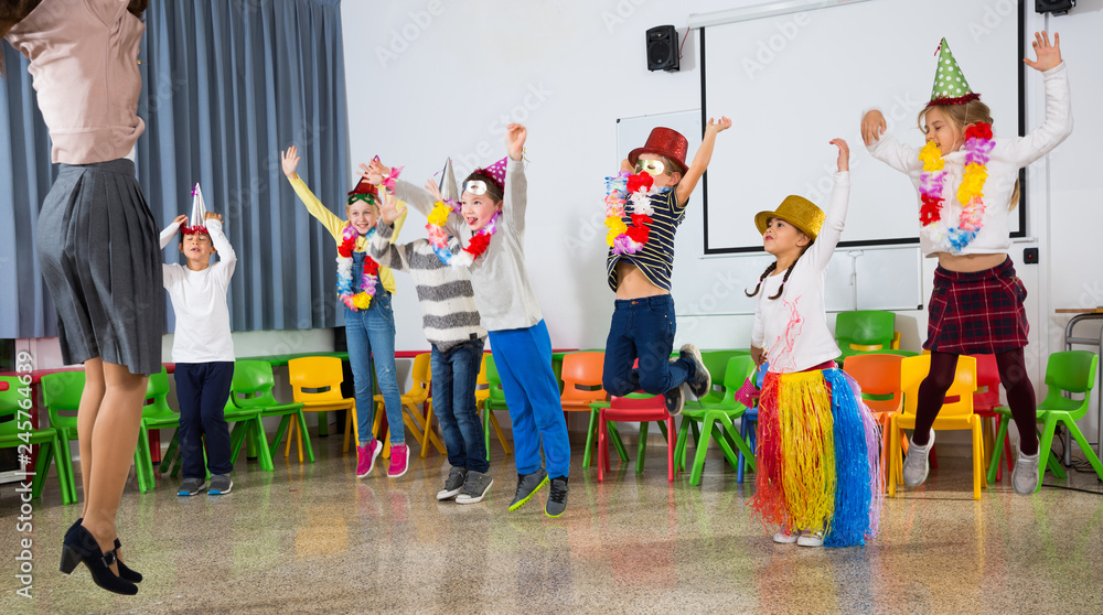 Obraz premium Pupils and teacher in festive hats jumping