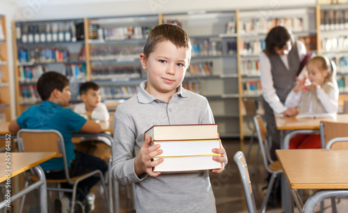 Smiling boy standing with pile of books