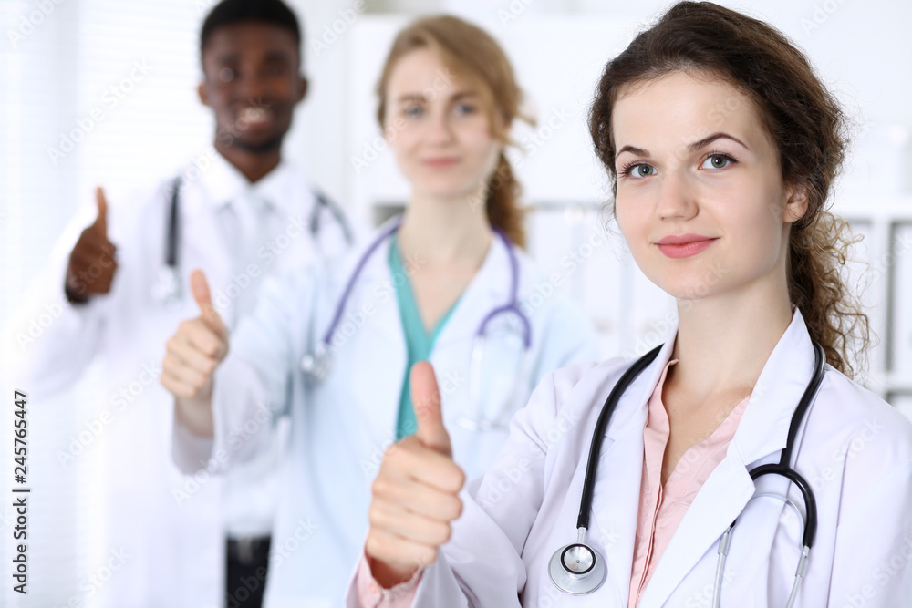 Happy doctor woman showing Ok sign with medical staff at the hospital. Multi ethnic people group Happy doctor woman showing Ok sign with medical staff at the hospital. Multi ethnic people group
