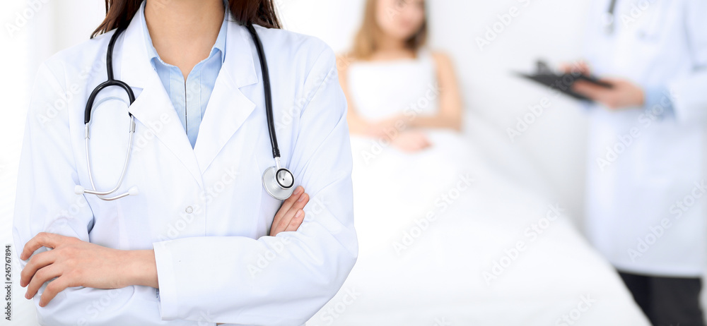 Female doctor with stethoscope standing upright with crossed arms, unknown physician at work. Medicine concept Female doctor with stethoscope standing upright with crossed arms, unknown physician at work. Medicine concept