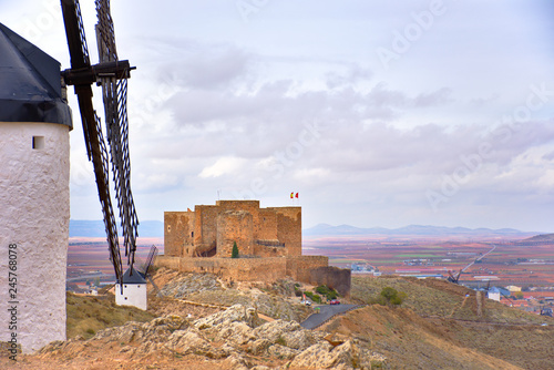 CONSUEGRA, SPAIN - NOVEMBER 22, 2018: Windmills of Don Quixote route, View of the medieval castle of the city of Castilla La Mancha in the background.