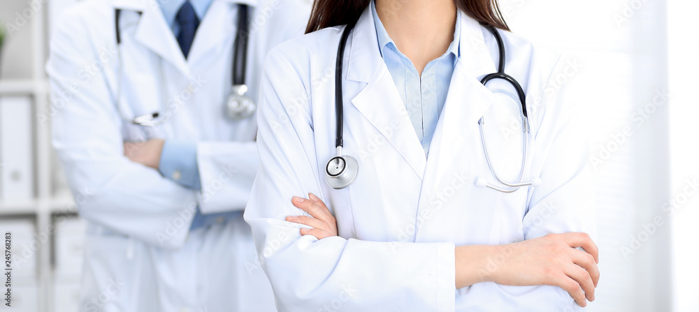 Female doctor with stethoscope standing upright with crossed arms, unknown physician at work. Medicine concept Female doctor with stethoscope standing upright with crossed arms, unknown physician at work. Medicine concept