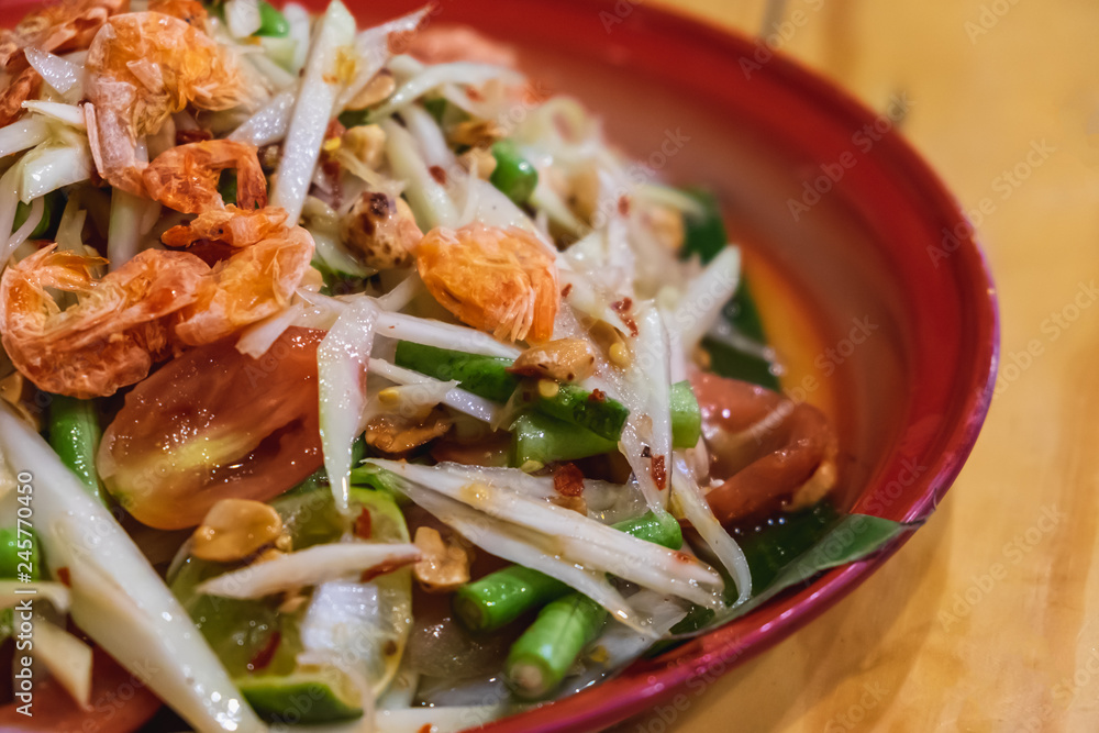 thai green papaya salad in red tray on wooden table thai green papaya salad in red tray on wooden table